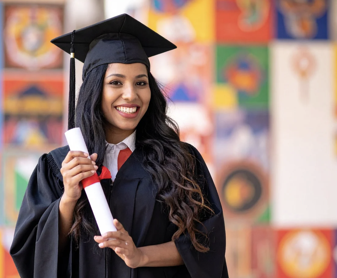 Students at graduation, smiling in caps and gowns.